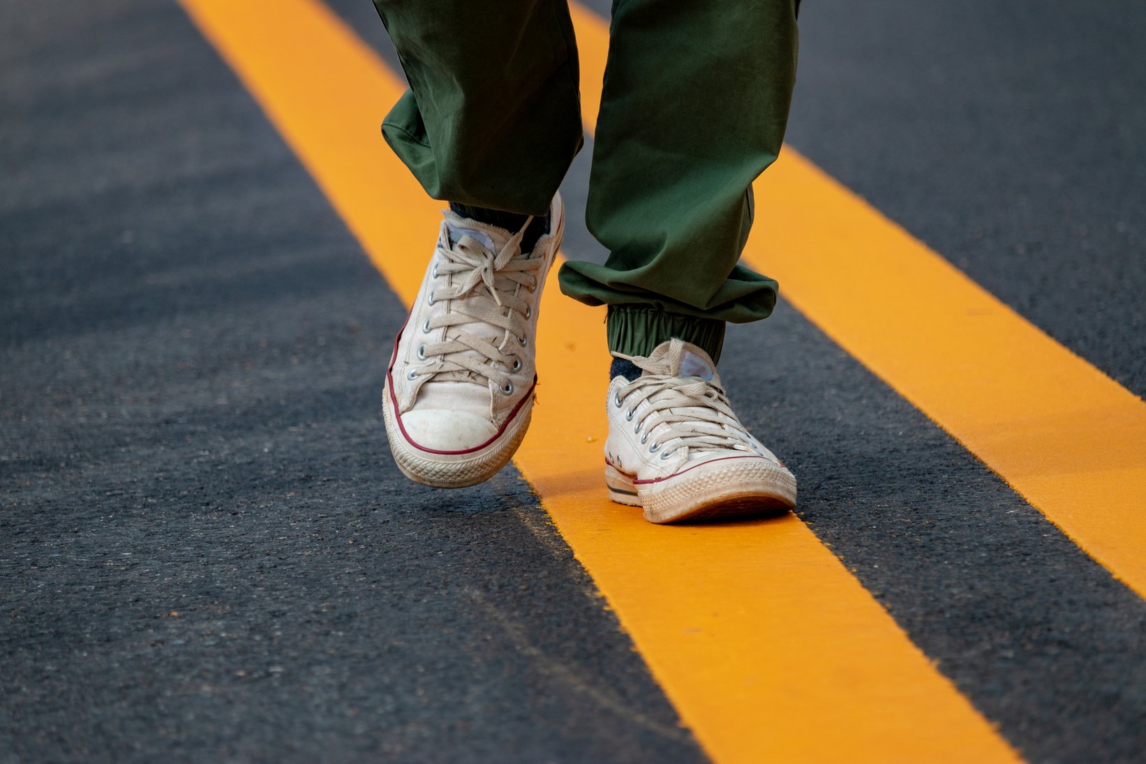 Person Walking Along the Road Lines Up Close